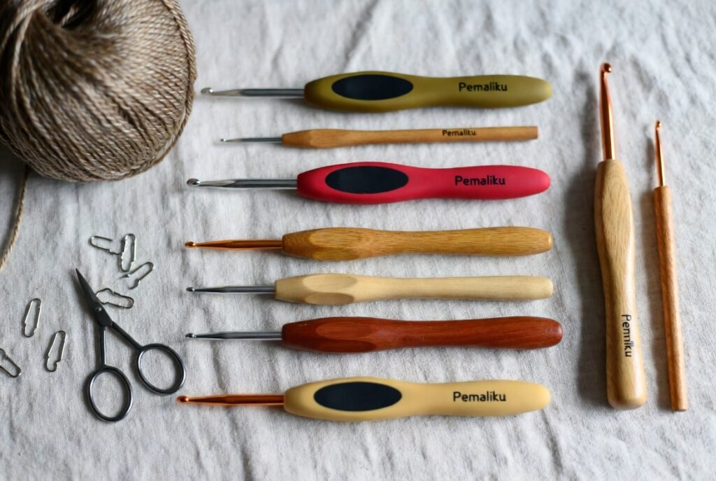 Crochet hooks displayed in different sizes and materials including ergonomic, metal, bamboo, and wooden crochet hooks used as essential crochet tools for beginners and professionals.