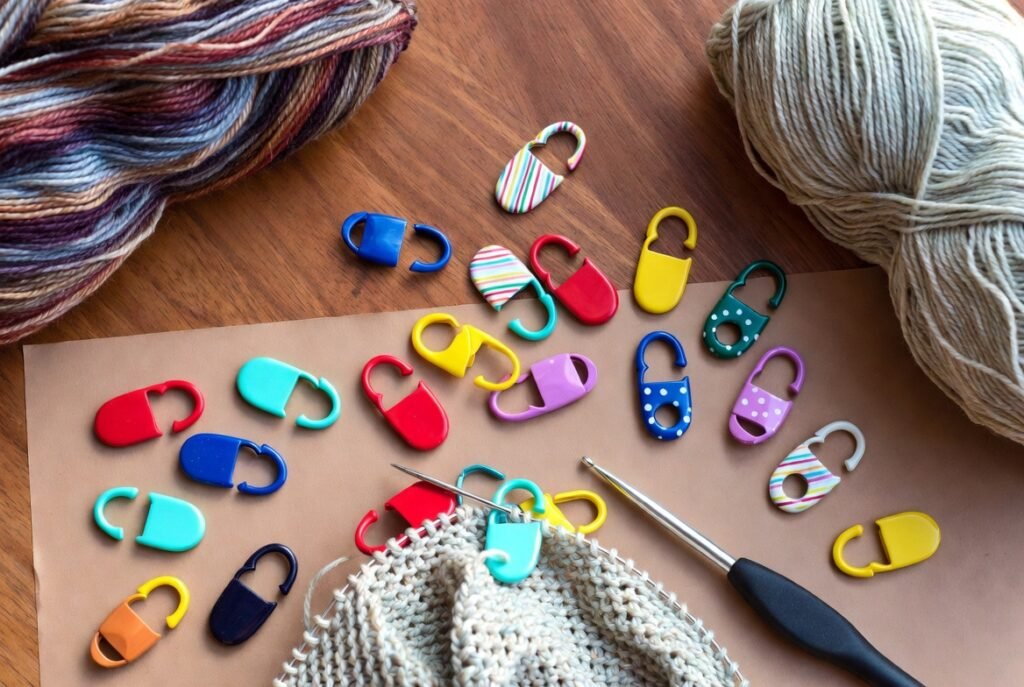 Colorful stitch markers clipped onto a crochet project, used as essential crochet tools for tracking rounds, rows, and pattern repeats in beginner and advanced crochet projects.