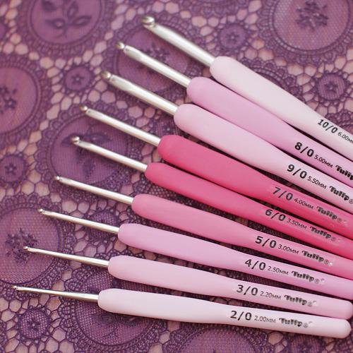 Tulip Etimo crochet hooks with ergonomic handles arranged on a light wooden surface.